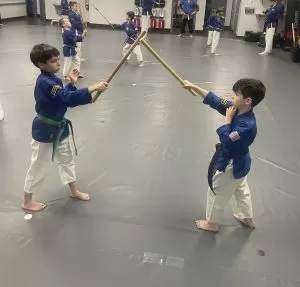 two students practicing with staffs